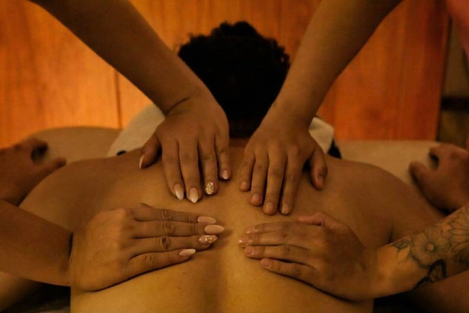 Masaje relajante con varias manos en la espalda